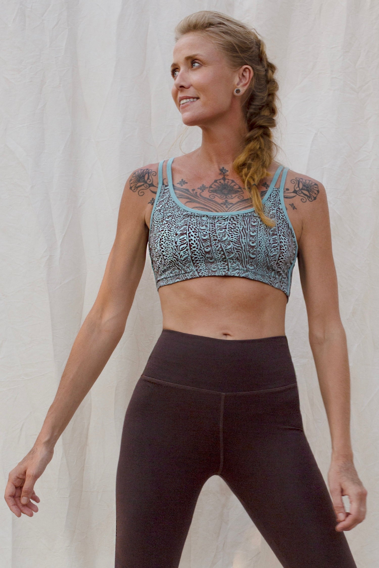 Woman wearing an Argus patterned sports bra and brown leggings against a plain background