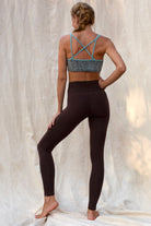 Person wearing a Argus patterned sports bra and brown leggings on a textured white background