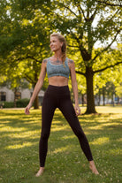 Woman wearing an Argus patterned sports bra and brown leggings in a sunny park