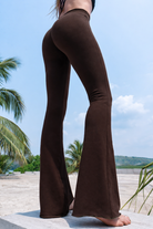 Brown bell-bottom pants worn by a person with a tropical background