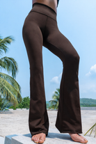 Woman wearing cotton stretch flares in dark brown colour with tropical plants on the back ground